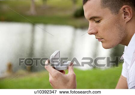 Stock Photo - A young man holding an engagement ring. Fotosearch