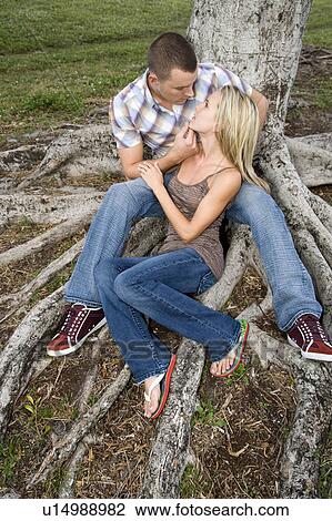 Stock Image - Two young lovers sitting beneath a tree. Fotosearch