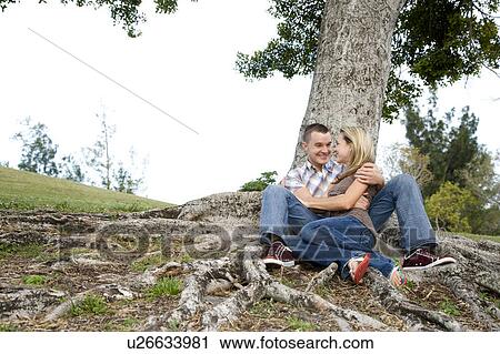 Two young lovers sitting beneath a tree View Large Photo Image Stock Image - Two young lovers sitting beneath a tree. Fotosearch