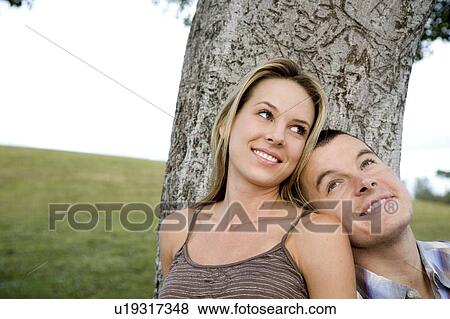 Stock Photo - Two young lovers sitting beneath a tree. Fotosearch