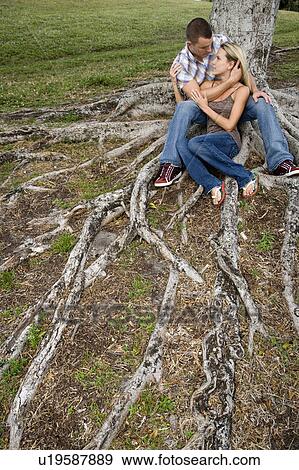 Stock Photo - Two young lovers sitting beneath a tree. Fotosearch