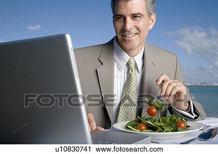 Stock Image - A businessman having lunch. Fotosearch