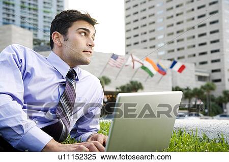 A businessman sitting in a park with his laptop View Large Photo Image Stock Photography - A businessman sitting in a park with his laptop. Fotosearch