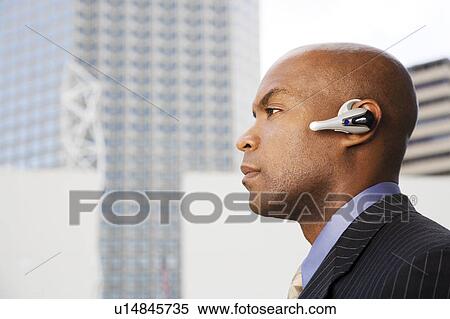 A businessman wearing a bluetooth headset View Large Photo Image Stock Photography - A businessman wearing a bluetooth headset. Fotosearch