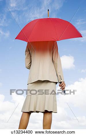 A businesswoman standing underneath an umbrella holding a mobile phone View Large Photo Image Stock Image - A businesswoman standing underneath an umbrella holding a mobile phone. Fotosearch