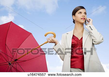 A businesswoman standing underneath an umbrella on a mobile phone View Large Photo Image Stock Photo - A businesswoman standing underneath an umbrella on a mobile phone. Fotosearch