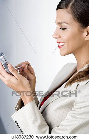Stock Image - A businesswoman using a PDA. Fotosearch
