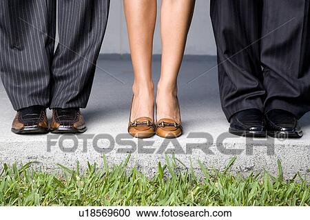 Stock Image - Close up of three business colleagues' feet. Fotosearch