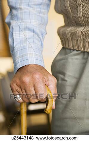 Stock Photo - An elderly man holding a walking stick. Fotosearch