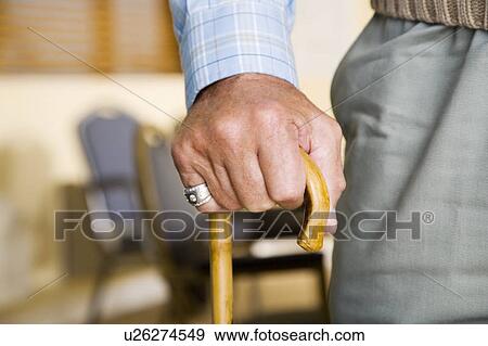Stock Photo - An elderly man holding a walking stick. Fotosearch
