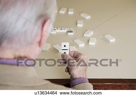 Picture - An elderly man playing dominoes. Fotosearch