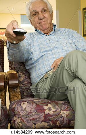 Stock Photo - An elderly man using a TV remote control. Fotosearch