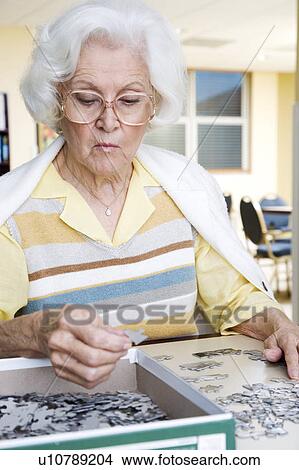 An elderly woman completing a jigsaw View Large Photo Image Picture - An elderly woman completing a jigsaw. Fotosearch