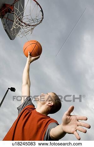 Stock Image - A teenage boy playing basketball. Fotosearch