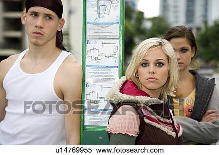 Stock Photography - Three teenagers standing at a bus stop. Fotosearch