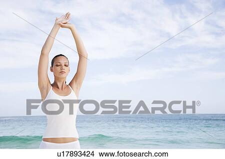 Picture - A young woman doing yoga on the beach. Fotosearch