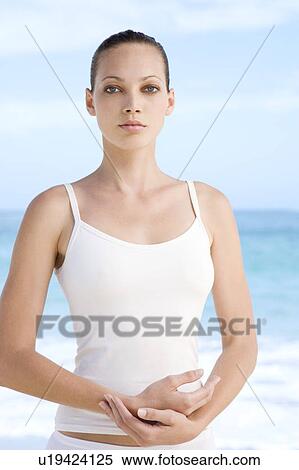 Stock Photography - A young woman doing yoga on the beach. Fotosearch