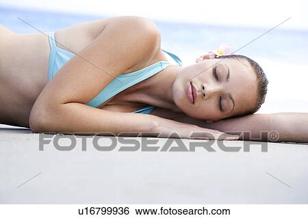 Stock Photograph - A young woman laying on the beach . Fotosearch
