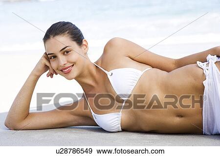 A young woman reclining on the beach View Large Photo Image Stock Photo - A young woman reclining on the beach. Fotosearch