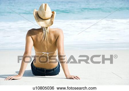 Stock Photograph - A young woman sitting on beach . Fotosearch