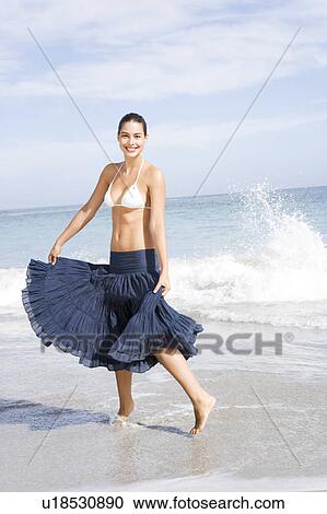 Stock Image - A young woman walking along the shore. Fotosearch