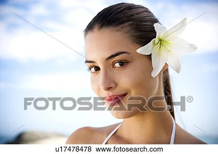 Stock Photo - Portrait young Hispanic woman with flower in hair. Fotosearch