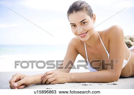 Stock Image - Portrait young woman lying on the sand. Fotosearch
