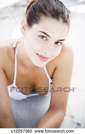 Stock Photography - Portrait young woman lying on the sand. Fotosearch