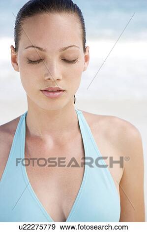 Stock Photo - Portrait young woman on the beach eyes closed. Fotosearch