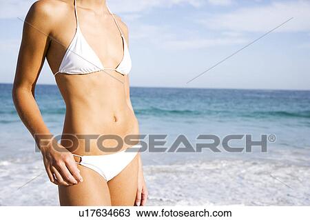 Young woman on beach in white bikini View Large Photo Image Stock Image - Young woman on beach in white bikini. Fotosearch