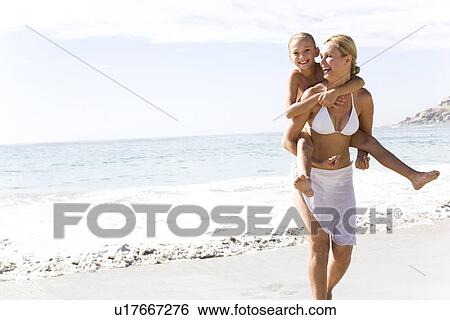A mother carrying daughter on the beach View Large Photo Image Stock Photograph - A mother carrying daughter on the beach. Fotosearch