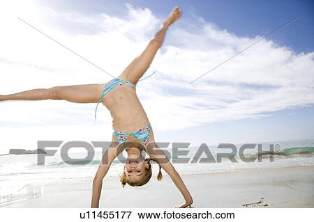 Stock Photo - A young girl cartwheeling on the beach. Fotosearch