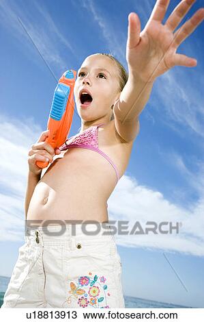Stock Image - A young girl playing on the beach. Fotosearch