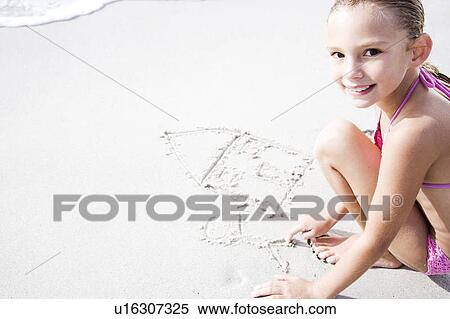Stock Photography - A young girl writing in the sand. Fotosearch