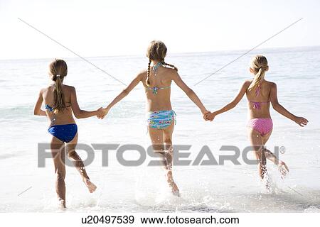 Three young girls running into the sea View Large Photo Image Stock Photo - Three young girls running into the sea. Fotosearch