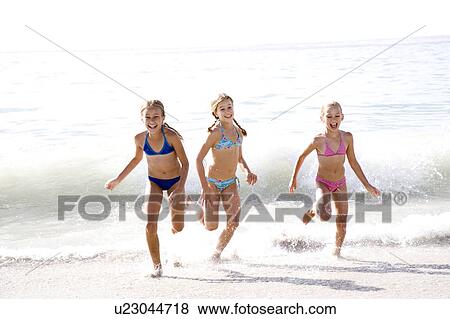 Stock Photo - Three young girls running out of the sea. Fotosearch