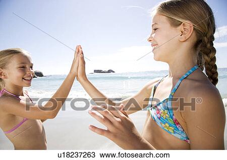 Stock Image - Two young girls playing on the beach. Fotosearch