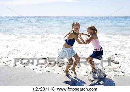 Two young girls playing on the beach View Large Photo Image Stock Photo - Two young girls playing on the beach. Fotosearch