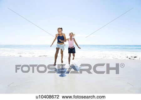 Stock Image - Two young girls running on the beach. Fotosearch