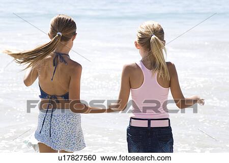 Two young girls running on the beach hand in hand View Large Photo Image Stock Image - Two young girls running on the beach hand in hand. Fotosearch