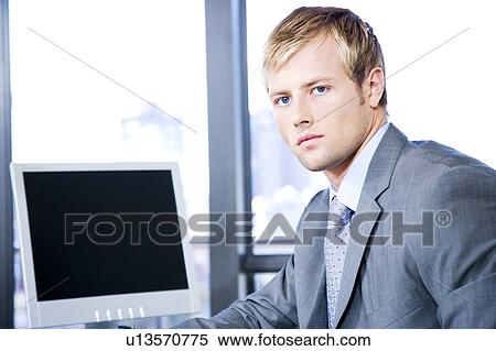 Businessman next to a computer screen on a modern office View Large Photo Image Stock Photography - Businessman next to a computer screen on a modern office. Fotosearch