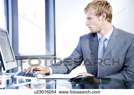 Picture - Businessman using a computer in a contemporary office building. Fotosearch