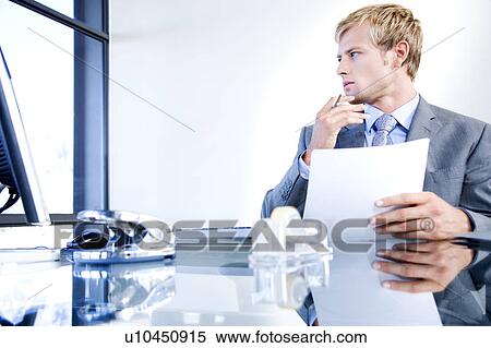 Stock Photography - Businessman with paperwork in a modern office. Fotosearch