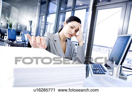 businesswoman looking stressed sat at her desk with paperwork View Large Photo Image Stock Image - businesswoman looking stressed sat at her desk with paperwork. Fotosearch