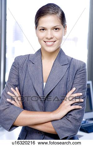 Stock Photograph - Businesswoman smiling with her arms folded, portrait. Fotosearch