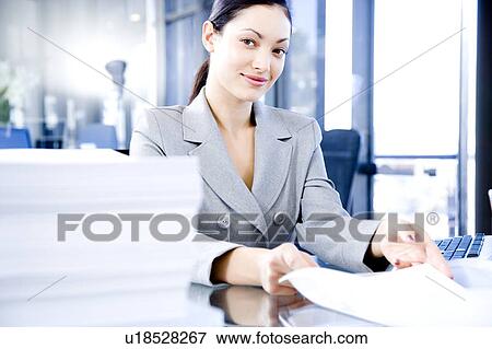 Smiling woman behind a desk full of paperwork View Large Photo Image Stock Photo - Smiling woman behind a desk full of paperwork. Fotosearch