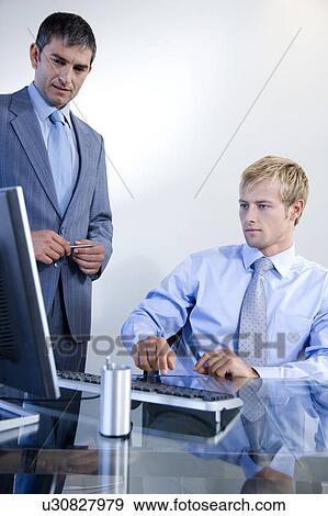 Two businessmen looking at a computer in a modern office View Large Photo Image Stock Photo - Two businessmen looking at a computer in a modern office. Fotosearch