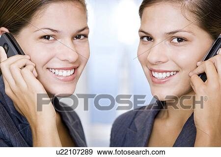 Two identical twin businesswomen using cellphones View Large Photo Image Stock Photo - Two identical twin businesswomen using cellphones. Fotosearch