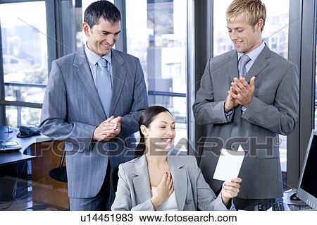 Stock Image - Two male colleagues congratulating a female colleague. Fotosearch