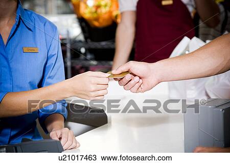Stock Image - Close up view of a customer paying by credit card in a supermarket. Fotosearch